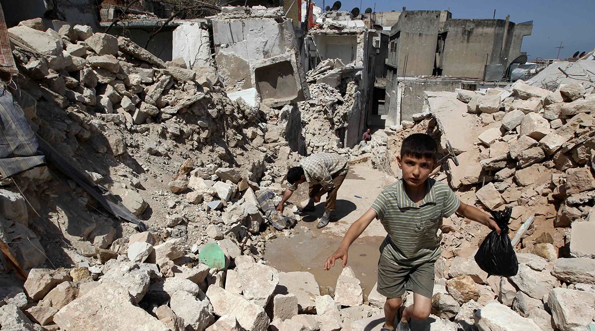 Image: A boy walks on the rubble of damaged buildings in Salqin city